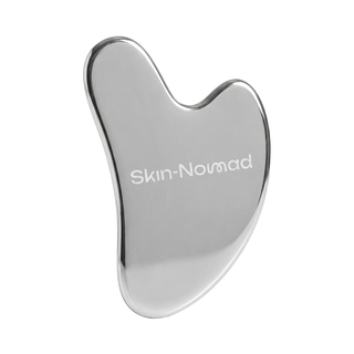 Silver gua sha tool with 'Skin Nomad' branding on a white background